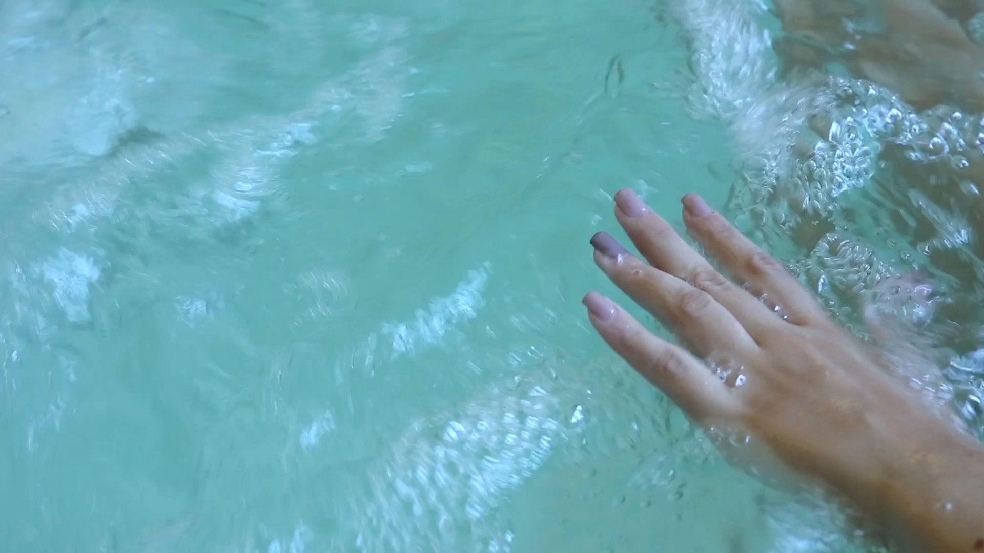 Mano immersa in acqua cristallina con bolle, creando un effetto rilassante.