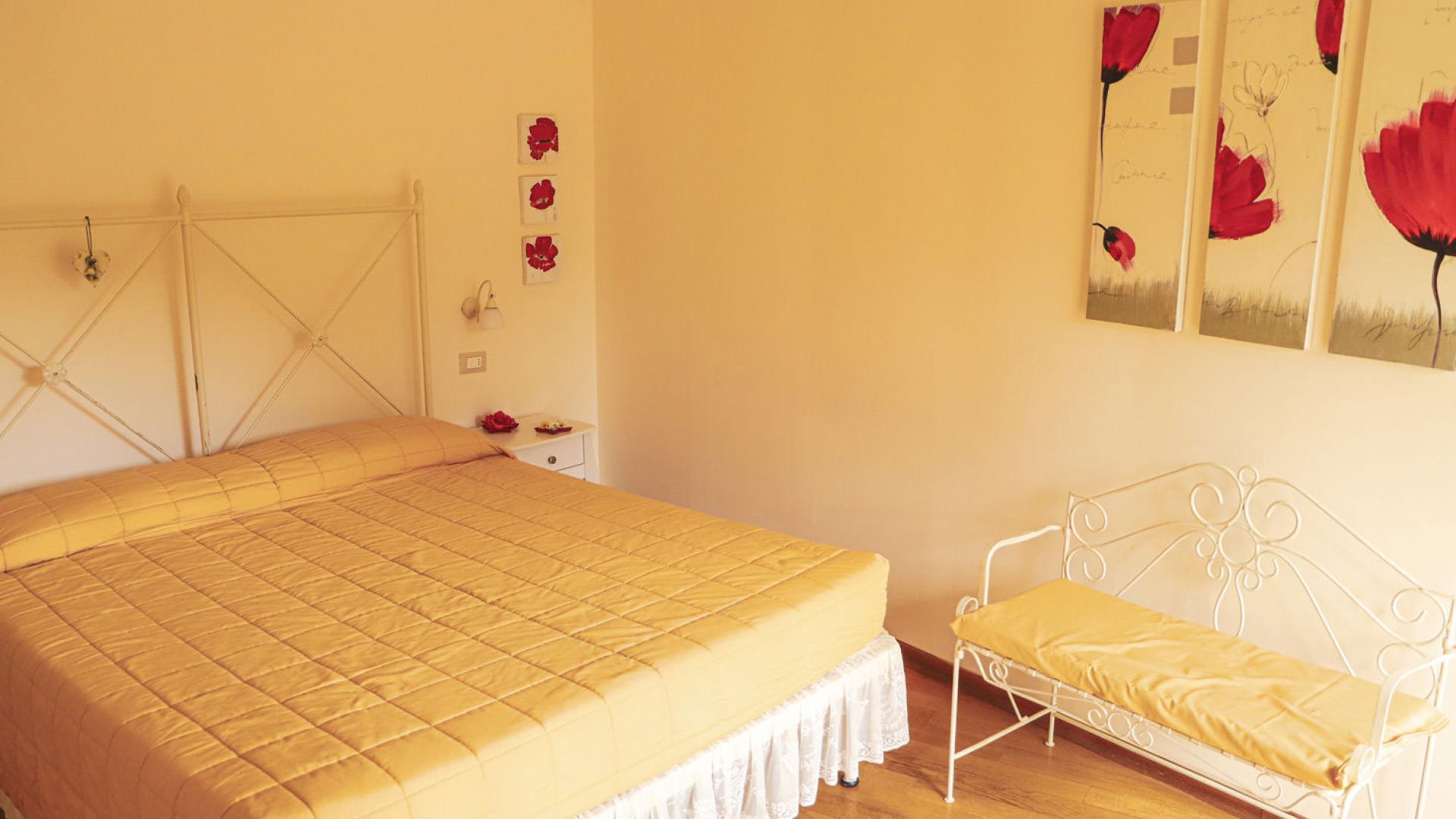 Camera da letto con letto matrimoniale, decorazioni floreali e panca bianca.