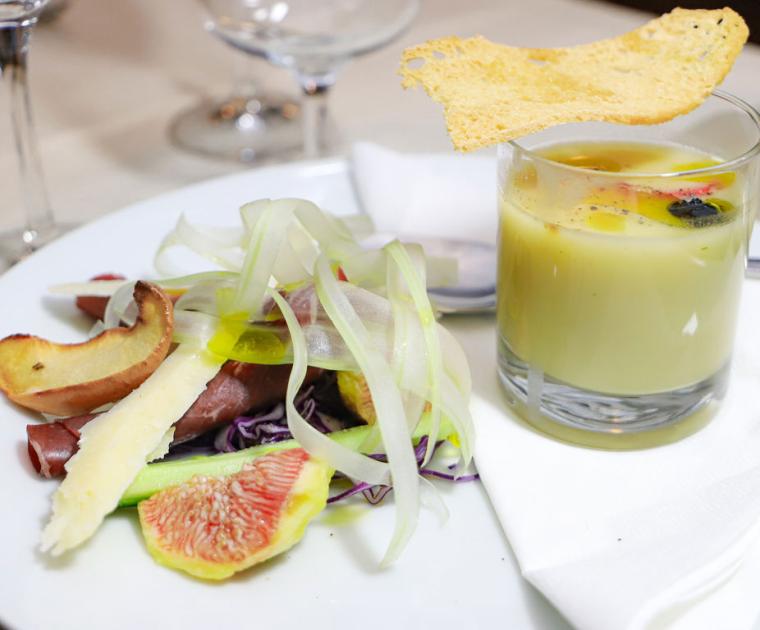 Piatto gourmet con insalata, fichi, formaggio e zuppa in bicchiere con crostino.