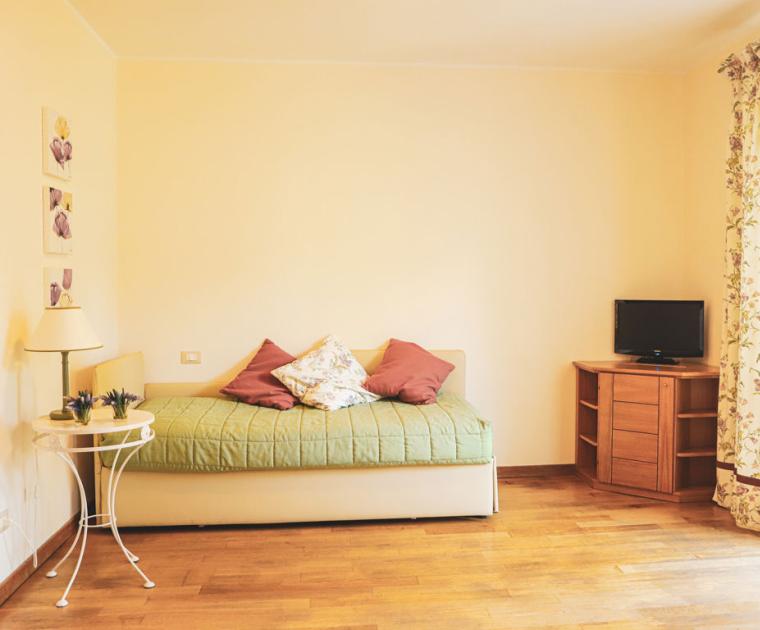 Camera accogliente con letto singolo, TV e decorazioni floreali.